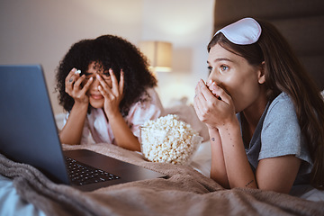 Image showing Laptop, movie and horror with friends and popcorn in bedroom for sleepover, bonding and streaming. Technology, internet and relax with shocked women at night for cinema, subscription or entertainment