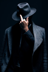 Image showing Mystery, middle finger or dark man in stylish outfit, fashion or suit posing isolated against a studio black background. Person, style and fashionable male or gangster with offensive gesture