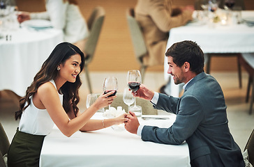 Image showing Love, wine and toast with a couple in a restaurant for their anniversary celebration or romantic dinner. Night, glasses or dates with a young man and woman celebrating an event together with a cheers