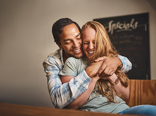 Image showing Happy couple, hug and smile for romance, embrace or relationship happiness at indoor restaurant. Young man hugging woman and smiling for fun love or dinner date spending bonding time at cafe together