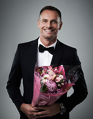 Image showing Portrait, man and bouquet of flowers, suit and happiness for Valentines day, romance and on grey studio background. Face, male and guy with floral gift, smile and gesture for love, romantic and happy