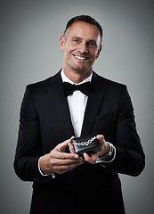 Image showing Jewelry, man and portrait of a model with a smile and valentines present in a studio. Isolated, gray background and person in a suit with happiness holding a necklace gift feeling love and classy