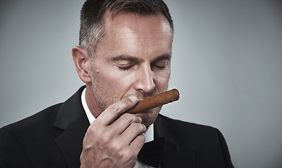 Image showing Suit, luxury and man smell cigars for smoking habit on gray background for mafia, power and success mockup. Mafia, business gangster and face of senior male with cigarette for smoke, relax and calm