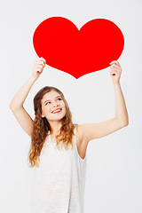 Image showing Love, showing and girl with a cardboard heart isolated on a white background in a studio. Smile, care and happy woman holding a paper shape for romance, attraction and valentines day on a backdrop