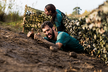 Image showing Athletes crawling through mud