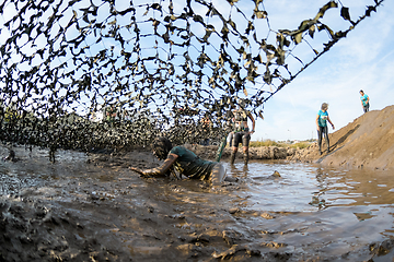 Image showing Athletes crawling through mud