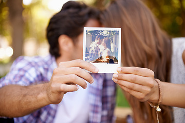 Image showing Couple, photograph and valentines day date with love, kiss and affection in outdoor park for memory. Happy man and woman together on a picnic with polaroid paper picture in hands on holiday outdoor