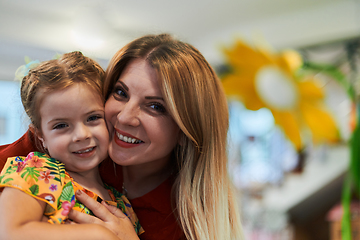 Image showing A cute little girl kissing and hugs her mother in preschool