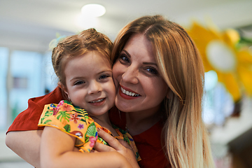 Image showing A cute little girl kissing and hugs her mother in preschool