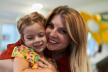 Image showing A cute little girl kissing and hugs her mother in preschool