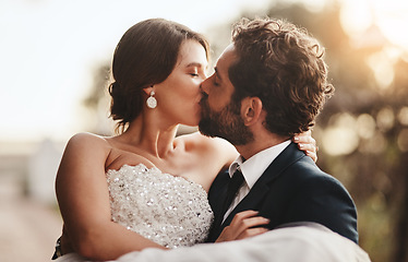 Image showing Love, wedding and kiss with a couple outdoor on their marriage day together for romance or tradition. Event, celebration or married with a birde and groom kissing outside after their ceremony