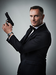Image showing Portrait, gun and man in studio with weapon for power, crime or secret mission on grey background. Face, handgun and mature guy model ready to shoot with mockup, assassin or hitman aesthetic isolated