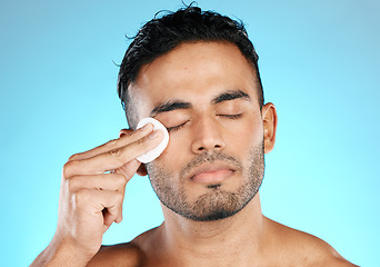 Image showing Man, cotton and man in studio for skincare, wellness and cleaning while grooming on blue background. Faical, pad and male skin model relax with luxury, cosmetics and product, hygiene and isolated