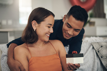 Image showing Love, surprise and man giving his wife a gift for valentines day, anniversary or romantic event. Happy, smile and husband giving his woman a present while relaxing on the sofa in living room at home.