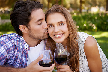 Image showing Couple portrait, wine or cheek kiss on picnic date, valentines day or romance bonding in nature, park or garden. Smile, happy woman and man with alcohol drinks glass for love anniversary celebration