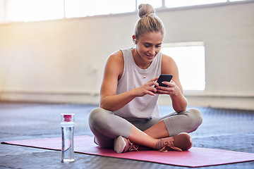 Image showing Exercise, relax and woman with phone on floor reading email or text after yoga workout at gym. Health, pilates and technology, girl on ground with smartphone checking fitness app online siting on mat