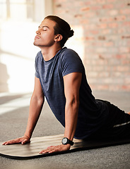 Image showing Calm, yoga and man stretching in a gym with fitness, exercise and workout for wellness. Breathing work, pilates and body stretch of a athlete on the ground of a health and training center to relax