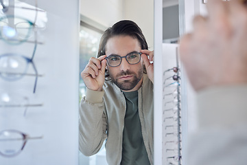 Image showing Optometry, glasses choice and man check mirror for vision, eye care and customer experience in store with lens frame. Young client or person eyes healthcare, retail and shop test for optical wellness