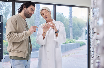 Image showing Doctor, optician help man or glasses for clear vision, friendly services or conversation. Optical store, woman talking to male customer or shopping for eye care, discussion or new prescription lenses