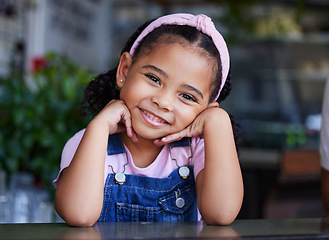 Image showing Black child, face and girl portrait with a smile, happiness and cute clothes with hands for headshot. Happy kid at a table for fashion, positive mindset and blurred background at cafe or home