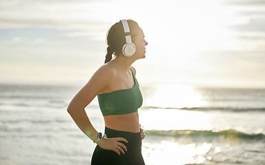 Image showing Sunshine headphones and woman on beach, fitness and streaming music for peace, balance or resting. Female, lady or confident athlete with headset, sunlight or seaside for running, workout or exercise