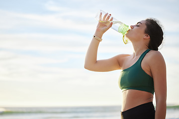 Image showing Drinking water, fitness and woman on beach for running, exercise or outdoor workout nutrition, health and wellness. Liquid bottle for diet, goals and tired sports runner, athlete or person by sea