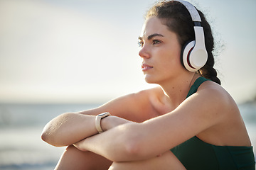 Image showing Headphones, fitness and relax woman on beach for wellness, mental health and health in morning sky mockup. Thinking, ideas and calm sports person listening to music or peace podcast by ocean or sea