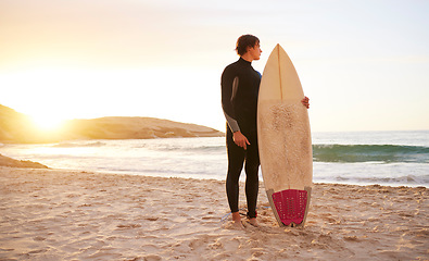 Image showing Surfer, surf and man with surfboard at the beach, sea and ocean in sunset or the morning with mockup space. Young, ready and male in swimsuit on a sunny day on the sand, shore and water in summer