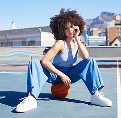 Image showing Basketball, fashion and portrait of black woman on court floor with trendy, urban style and edgy clothes in city. Sports, fitness and girl model outdoors with ball for freedom, energy and cool outfit