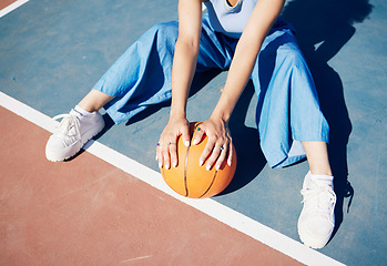 Image showing Basketball, hands and woman on the outdoor court floor with urban fashion for influencer beauty. Sport, model and young person sitting with gen z clothes with sports game equipment in summer