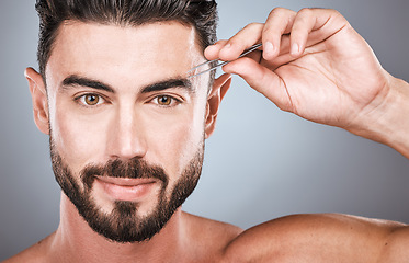 Image showing Face portrait, eyebrow and man with tweezers in studio isolated on a gray background for wellness. Health, hair removal and male model with facial product to pluck eyebrows for grooming and beauty.