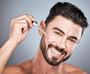 Image showing Man, face and cosmetic serum for skincare, beauty and facial care, oil product in hand isolated on studio background. Portrait, smile and moisturizer, wellness and dermatology for healthy skin glow