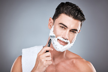 Image showing Face, razor and man with shaving cream in studio isolated on a gray background. Beard care, towel and portrait of male model with facial product, foam or gel to shave for wellness and hair removal