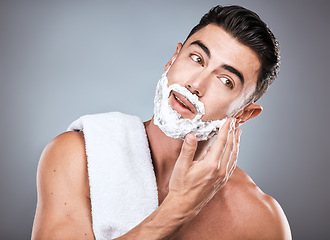 Image showing Face, shave foam and grooming with a man model in studio on a gray background for hair removal. Beard, hand and skincare with a handsome young male in the bathroom for shaving in the morning