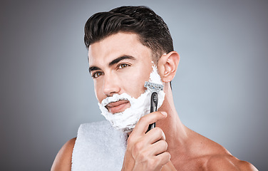 Image showing Face, shaving cream and man with razor in studio isolated on a gray background. Skincare, cleaning and thinking male model with facial product, foam or gel to shave for wellness, health and hygiene.