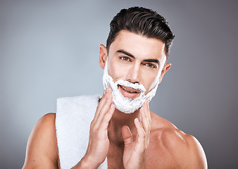 Image showing Face, shaving cream and grooming with a man model in studio on a gray background for hair removal. Shave, hands and skincare with a handsome young male in the bathroom for a shave in the morning