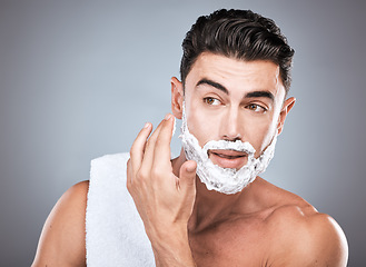 Image showing Face, shaving foam and grooming with a man model in studio on a gray background for hair removal. Thinking, hand and skincare with a handsome young male in the bathroom for a shave in the morning