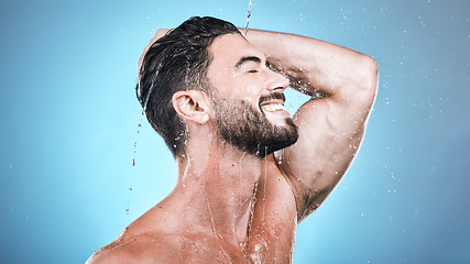 Image showing Face skincare, water splash and man in shower in studio isolated on a blue background. Wellness, dermatology and happy male model cleaning, washing and bathing for healthy skin, self care and hygiene