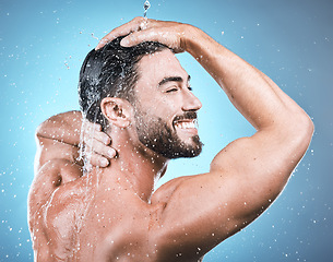 Image showing Back skincare, water splash and man in shower in studio isolated on a blue background. Wellness, dermatology and face of happy male model cleaning, washing and bathing for healthy skin and hygiene.