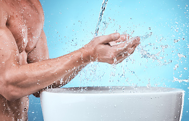 Image showing Water splash, washing hands and cleaning man in studio isolated on a blue background for wellness, healthy skin or hydration. Skincare hygiene, dermatology and male model bathing to remove bacteria.