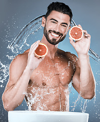 Image showing Portrait, water splash and man with grapefruit in studio isolated on a blue background. Skincare, vegan fruits and happy male model washing or cleaning food for hygiene, healthy diet and vitamin c.