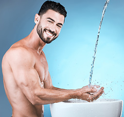 Image showing Water splash, portrait and man cleaning hands in studio isolated on a blue background for wellness, healthy skin or grooming. Hygiene dermatology, skincare and male model bathing or washing hand.