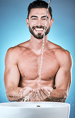 Image showing Portrait, water splash and man cleaning hands in studio isolated on a blue background for wellness, healthy skin or grooming. Hygiene dermatology, skincare and male model bathing or washing hand.