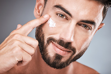 Image showing Skincare, applying and portrait of a man with face cream isolated on a grey studio background. Beauty, grooming and model with facial sunscreen for body dermatology, hygiene and sun protection