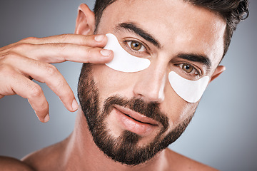 Image showing Face, skincare and man with eye patches in studio isolated on a gray background for wellness. Portrait, dermatology and male model with cosmetics, facial treatment or mask product for healthy skin.