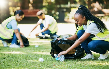 Image showing Volunteer group, nature park and cleaning for community service for clean environment, recycling and pollution. Black woman happy to help people with plastic bottle and trash bag outdoor green grass