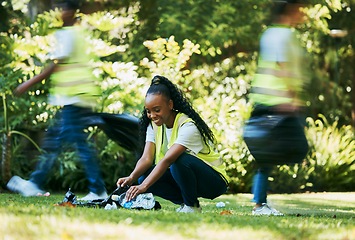 Image showing Volunteer, plastic and black woman cleaning park as community service for recycling and pollution. Ngo person happy to help group with bottle, dirt and trash bag outdoor in green nature environment