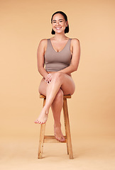 Image showing Portrait, beauty and an asian woman on a chair in studio on a beige background for natural body positivity. Model, underwear and an attractive young female sitting on a stool with confidence