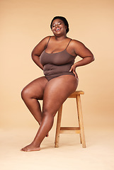 Image showing Portrait, wellness and plus size with a model black woman posing on a chair in studio on a beige background. Beauty, underwear and natural with a female sitting on a stool for body positivity