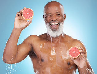 Image showing Black man, portrait smile and fruit for nutrition, vitamin C or skincare hydration against a blue studio background. Happy African American male smiling and holding grapefruit for health and wellness